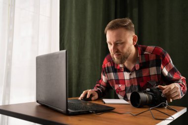 Fotoğrafçı dizüstü bilgisayardan dosya yüklüyor. Modern ofiste çalışan fotoğrafları kontrol ediyorum. Görüntülerini dizüstü bilgisayardan düzenliyor. Boşluğu kopyala