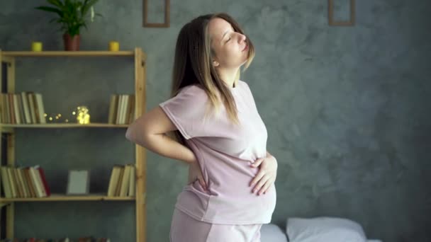 Desconforto durante a gravidez. bela mulher grávida tocando sua barriga e segurando uma mão em suas costas. Gestantes com dor lombar, estresse, ansiedade — Vídeo de Stock