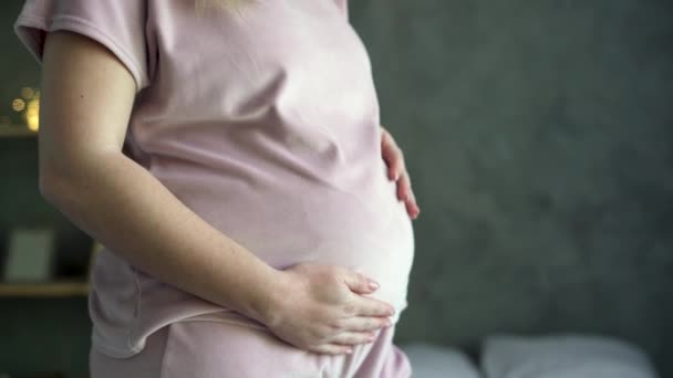 Mujer embarazada feliz de pie en el dormitorio sosteniendo y acariciando su gran vientre en casa, de cerca, el embarazo de la mujer joven disfrutando con la vida futura relajarse, maternidad y embarazada — Vídeo de stock