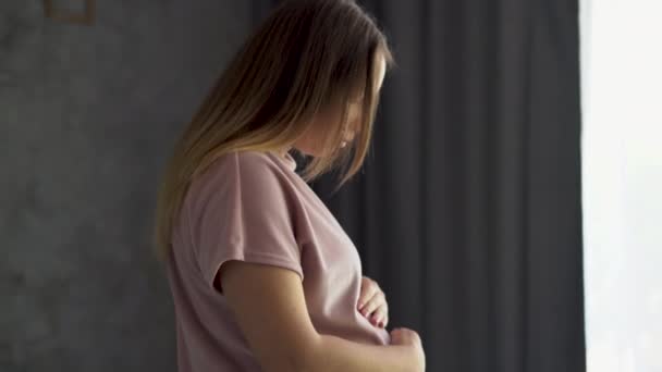 Gravid kvinde føler sig glad derhjemme. Ung forventer mor holder baby i gravid mave. Kvinde graviditet koncept og barsel prænatal pleje. – Stock-video