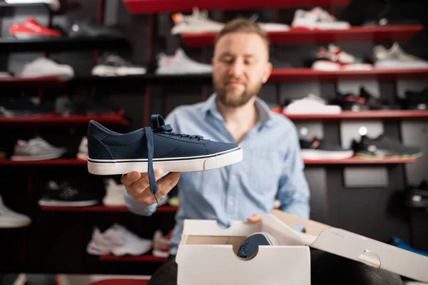 A man is shopping in a sporting goods store. The guy buys sneakers. Buying adventure shoes by a client. Close-up.