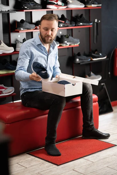 A man is shopping in a sporting goods store. The guy buys sneakers chooses the shoe model and size. Buying adventure shoes by a client. copy space.