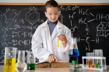 Kız öğrenci laboratuarda deney yapıyor. Okulda kimya öğreniyorum. Laboratuvarda kimyasal reaktörler var. Bilim ve eğitim kavramı.