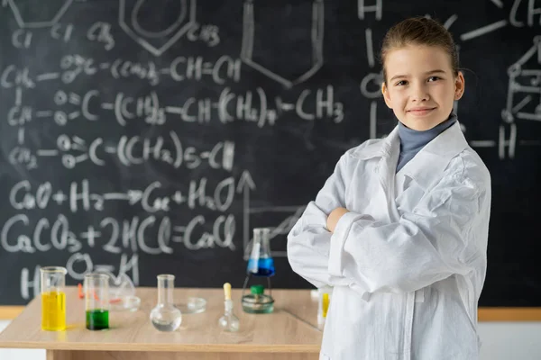 穿着实验室外套 戴着化学瓶的女科学家 背景在学校黑板上 手绘科学公式 回到学校的概念 — 图库照片