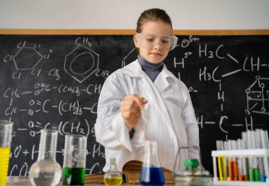 Okul laboratuarında kimyasal deneyler yapan kız öğrenci, okul çocukları için kimya sınıfında bilimsel deneyim, eğitim ve bilim konsepti