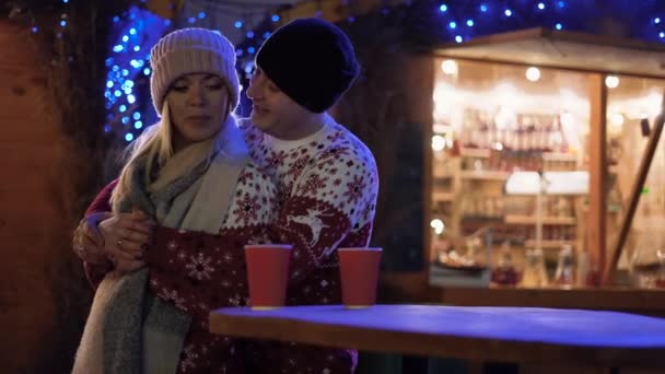 浪漫的夫妻在圣诞节的夜晚走在大街上 喝着热饮 情投意合的男女在一起共度寒假时拥抱在一起 开心地笑着 — 图库视频影像