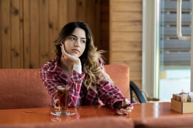 Akıllı telefonu ve restoranda çayı olan üzgün, yakışıklı bir kız. eğlence, teknoloji, yaşam tarzı ve insan konsepti