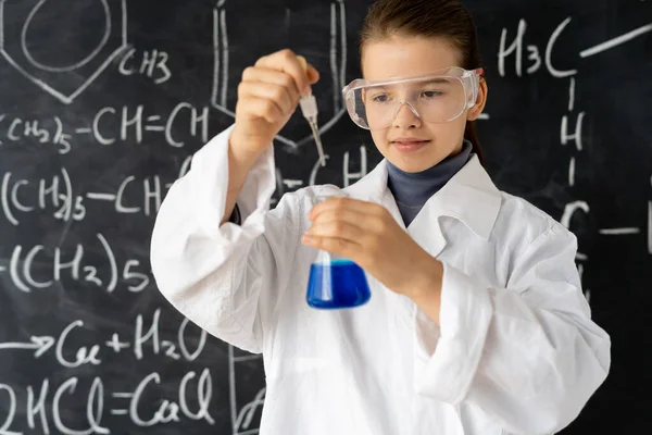 Portret of serious girl in white uniforms conducting chemical experiments in a laboratory. Young scientists. Natural sciences. school education of children. Back to school concept.