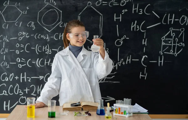 Experiments in a chemistry lab. serious little student conducting an experiment in the laboratory. girl makes a chemical experiment in a chemistry lesson