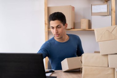 Müslüman erkek işyeri sahibi merkezde oturuyor. bilgisayar, çevrimiçi pazarlama paketleme kutusu teslimatı, KOBİ e-ticaret tele pazarlama kavramı.