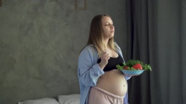 Mutlu hamile kadın kahvaltıda sebze salatası yiyor. Hamilelik, sağlıklı gıda ve insan kavramı