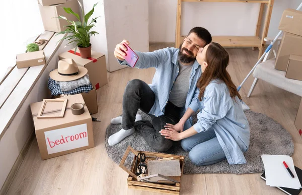 joyful attractive carefree lovely cute couple taking picture in new apartment. photo on the smartphone. Photographer partners move house concept.