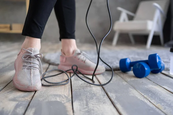 woman feet on the floor after exercising with dumbbell and jump rope at home. Concept of healthy and sport