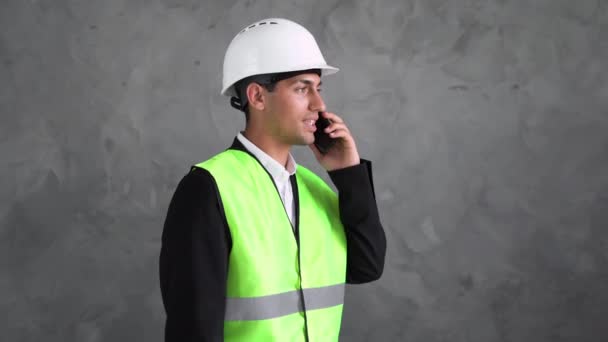 年轻的阿拉伯男性建筑师 戴着白色建筑头盔 用智能手机说话 一个穆斯林工头打了一个电话 复制空间 — 图库视频影像