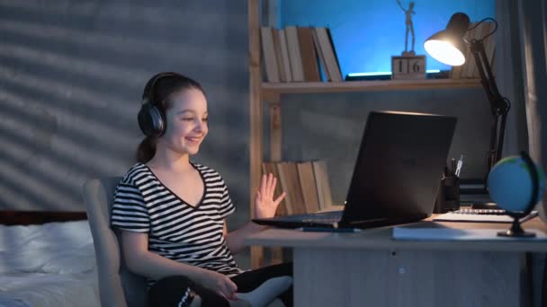 소녀는 헤드셋 노트북을 사용하여 온라인 선생님 공부하고 있습니다 밤늦게 헤드폰을 — 비디오
