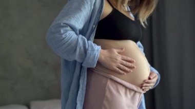 Mutlu hamile kadın karnını okşuyor ve doğmamış bebekle oynuyor, rahat bir odada hamile karnı, hamileliği ve bakım konseptiyle ilgilenen anne.