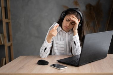 Evde dizüstü bilgisayarla çalışırken başı ağrıyan genç İspanyol kadın, bilgisayar ve kulaklıkla çalışan stresli kız.