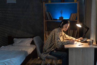 Asyalı kız İnternet üzerinden okuyor, öğrenci kız evde tablet bilgisayar ve kulaklık kullanıyor. eğitim, teknoloji, serbest çalışma, aşırı çalışma ve insanlar konsepti