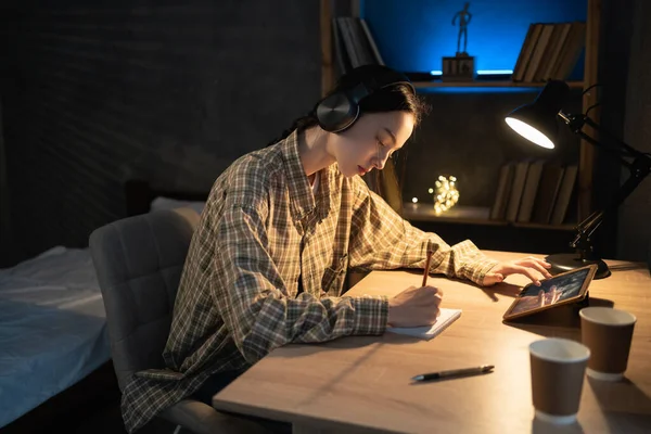 Asyalı kız geceleri tabletle internette çalışıyor. Ev konseptinde online öğrenim görüyor.