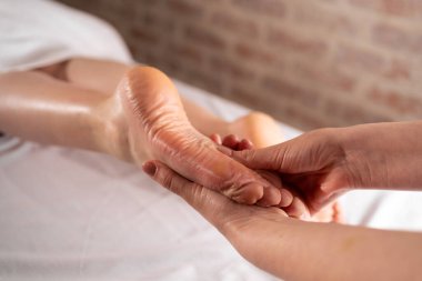 Güzellik salonunda ayak masajı yaptıran genç bir kadın.