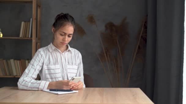 女性博主在社交网络上阅读评论 使用现代电话机 与笔记本电脑坐在一起工作的地方 女生聊天聊天 — 图库视频影像