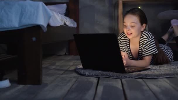 小女孩躺在地板上 在黑暗中观看笔记本电脑上的电影 与朋友 孩子和科技概念聊天 — 图库视频影像