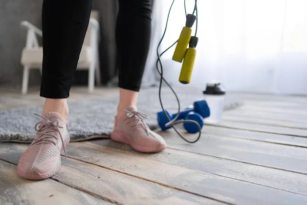 woman feet on the floor after exercising with dumbbell and jump rope at home. healthy and sport concept