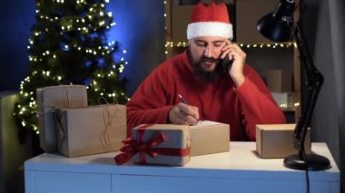 Küçük işletme sahibi, Noel Baba kostümlü, sakallı Hintli ev sahibi telefonla mal siparişi alıyor. Adresi kutunun üzerine yaz. Noel indirimi kavramı.