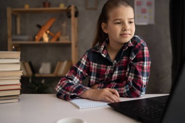 Laptop kullanarak ev okulu. Kafkasyalı küçük kız öğrenci uzaktan toplantıyla sanal internet dersini okul öğretmeninden öğreniyor. Liseli kız çevrimiçi ders izliyor ve evden ders çalışıyor..