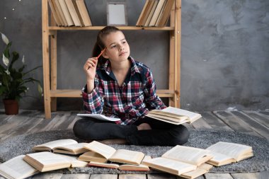 Beyaz kız öğrenci kütüphanede ya da evde çocuk resimleri okuyor ya da öğreniyor. Zeki okul çocuğu ödünç kitap seçiyor. Okul eğitimi ve okur yazarlık kavramı