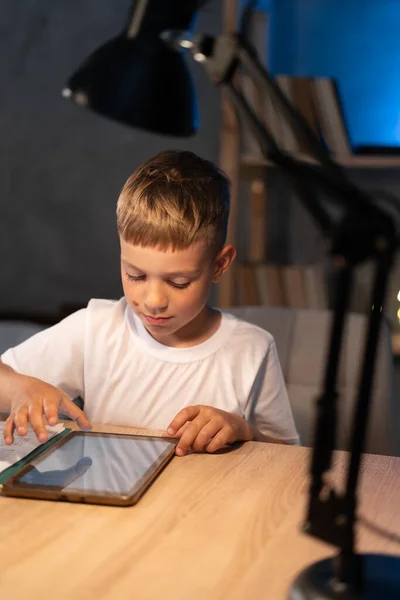 Menino Olhando Para Tablet Digital Enquanto Sentado Mesa Noite Criança — Fotografia de Stock