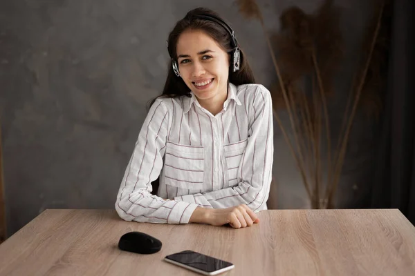 Smiling hispanic student, worker in headphones. Friendly young woman talking online, having video conference or call, speaking looking at camera. Video call screen