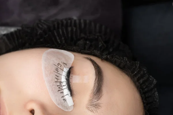 Eyelash extension procedure in beauty salon. Woman eye with long eyelashes. Lashes, close up