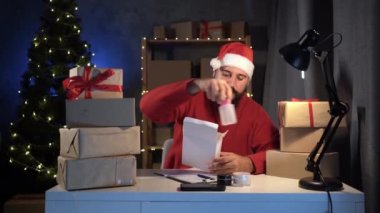 Hintli sakallı Noel Baba hediye kutuları paketliyor hızlı Noel indirimi için hazırlanıyor, atölye deposunda Noel Baba hediyeleri dağıtıyor ve hazırlanıyor.