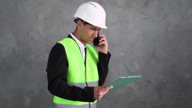 Genç çalışan Arap inşaat mühendisi bir tablet kullanarak bir proje planlıyor, modern bir bina inşa ediyor, bir plan okuyor. İnşaat alanında çalışan mimari veya mühendis.