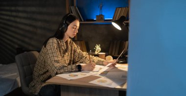 Çok çalıştım. Proje üzerinde çalışan Asyalı bir kız öğrenci, finansal belgeleri kontrol ediyor, gece geç saatlerde masada oturuyor, diyagramlı evraklara bakıyor, faturaları hesaplıyor.