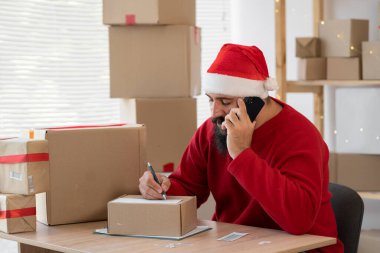 Hintli Noel Baba çevrimiçi işletme sahibi telefonda siparişi kabul eder, sipariş yazar, müşteri hediyeleri sipariş eder. Küçük işletme Noel indirimi. Boşluğu kopyala.