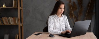 Evde bilgisayarla çalışan ciddi bir serbest çalışan genç kadın. İnternette okuyan çekici bir iş kadını, dizüstü bilgisayar, web sörfü bilgisi veya internet mağazasından alışveriş yapıyor. Pankart, boş alan