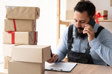 İnternetteki Hintli adam telefonda müşterinin siparişlerini onaylıyor. E-ticaret erkek işyeri sahibi depoda telefon kullanıyor. KME kavramı