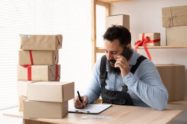 İnternetteki Hintli sakallı adam müşterinin siparişlerini onaylıyor. E-ticaret erkek işyeri sahibi depoda telefon kullanıyor. KME kavramı