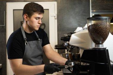 Kahve yapan genç baristanın portresi, kahve makinesiyle kahve yapmak, iş kavramı.