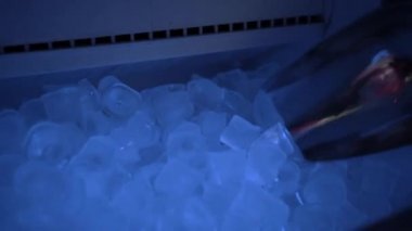 Buz makinesinden metal bir spatulayla buz topluyor.