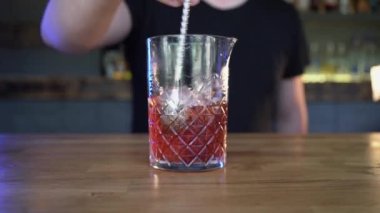 Profesyonel bir barmenin ellerini yakın plan çekerek tezgahta buz küplerini karıştırıyor.