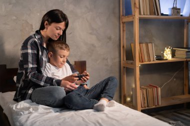 Çocuk, annesiyle yatakta otururken tablette çizgi film seyrediyor. Evde dijital tablet kullanmak. Yatak odasının içi..