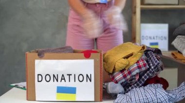 Donation box with Humanitarian aid with things for Ukrainian refugees. Charity and helping the poor and needy people. Stay with Ukraine. Ukrainian flag on a donation box. Volunteer stacking things