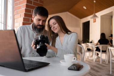 Kafede kamera ve dizüstü bilgisayar kullanarak çalışan fotoğrafçılar, kameradaki resimleri izliyorlar. Yeni modern teknoloji kavramı