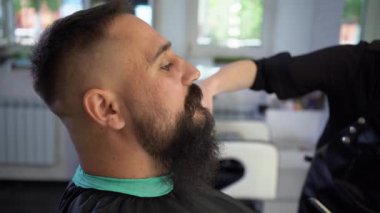 Bearded client visiting barbershop. Hairdressing scissors, barbershop. shaving a bearded man. Men with mustaches. Brutal guy and scissors. Advertising and barbershop concept