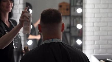 Kuaför kuaför kuaförde saç spreyi kullanan bir gencin saçını düzeltiyor. Elinde sprey olan berber. profesyonel stilist eğitim kavramı