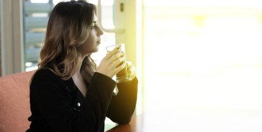 Esmer kız kafede sıcak çay içiyor. Güzel bir kadın limonlu çay içer ve kahvecide dinlenir. afiş, metin için boşluk