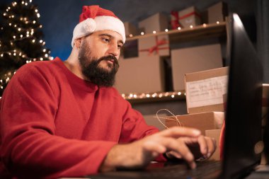 small business owner hindu freelance santa working at home office using computer, packaging box for online marketing and christmas gifts, e-commerce for small and medium business, christmas sale